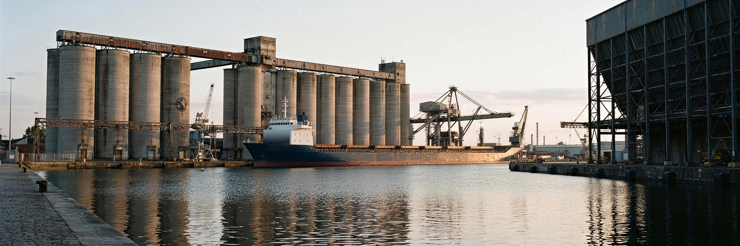 Concrete silos and a cargo vessel alongside a quay at first light